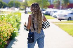 Rear of female in denim overalls holding skateboard