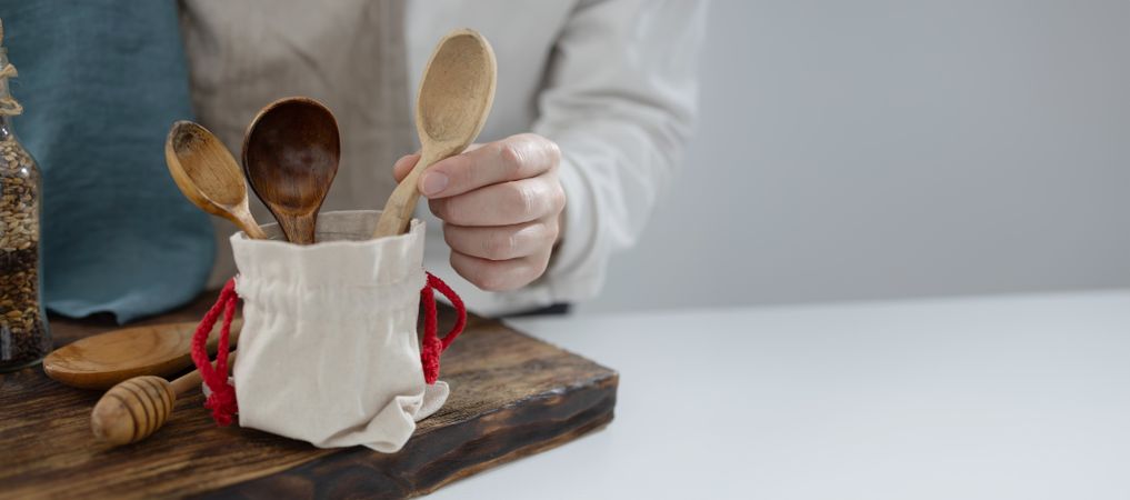 Hand taking wooden spoon from cup