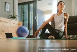 Healthy woman sitting on exercise mat and doing yoga 0Jonp5