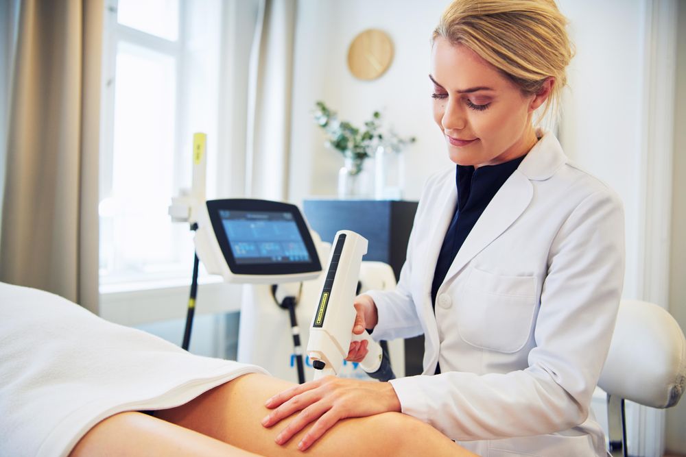 Female cosmetologist performing treatment on legs