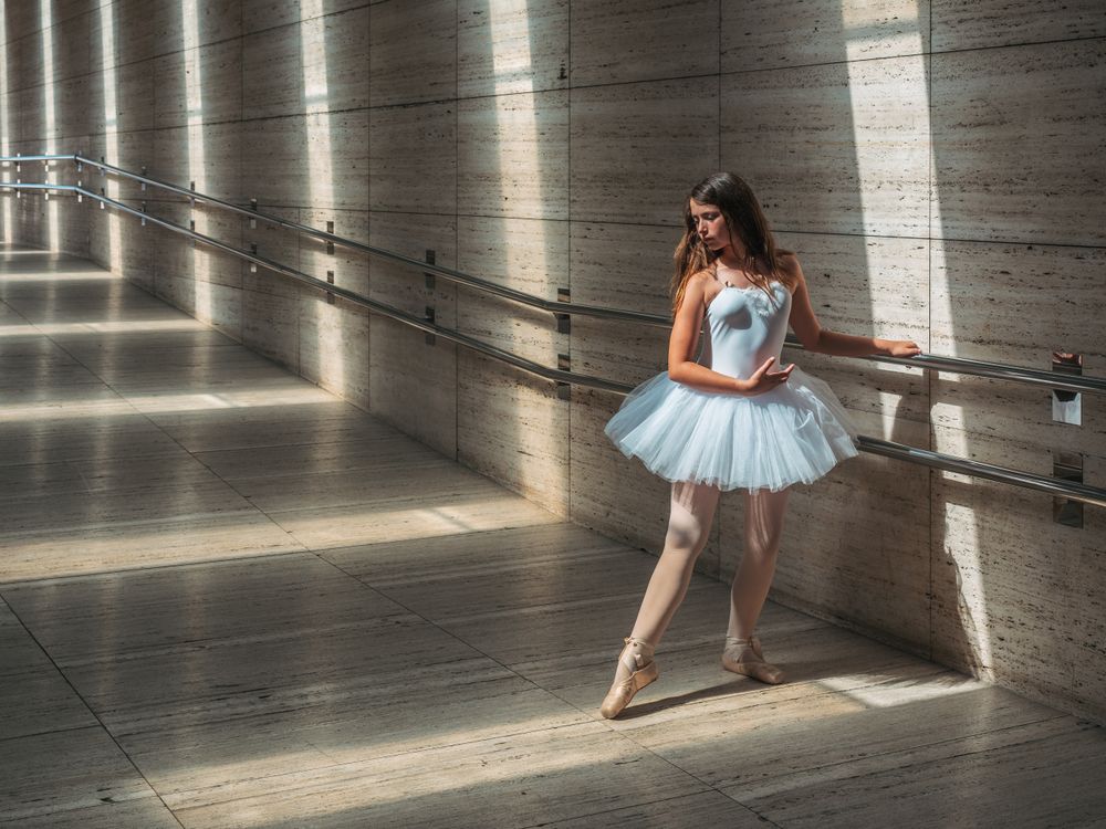 Ballerina doing ballet posing at rail in classroom