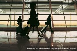 Travelers walking in front of large window at airport terminal 4Z9Rr5