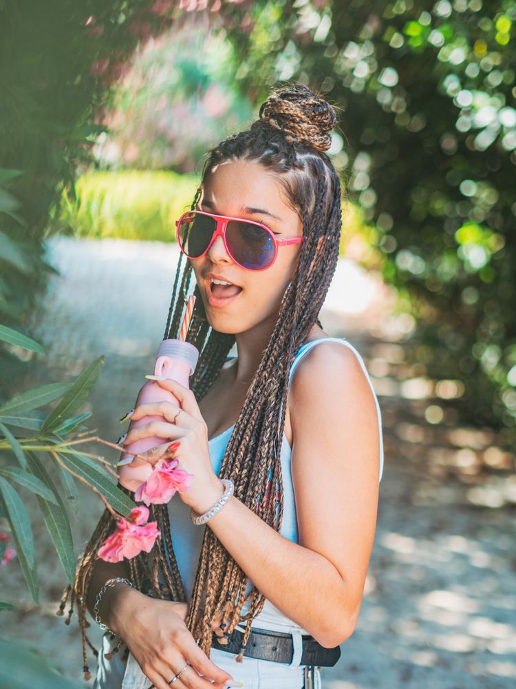 Stylish young woman with dreadlocks and beverage