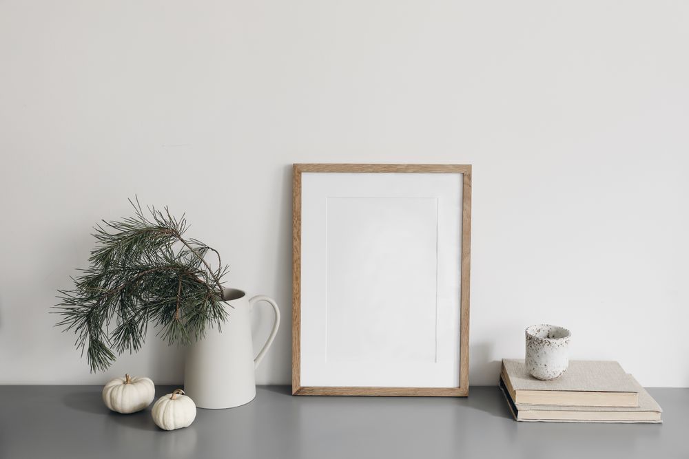 Wooden frame on desk with branches, books and decorative squashes