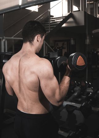 young fitness man doing machine weights in the gym