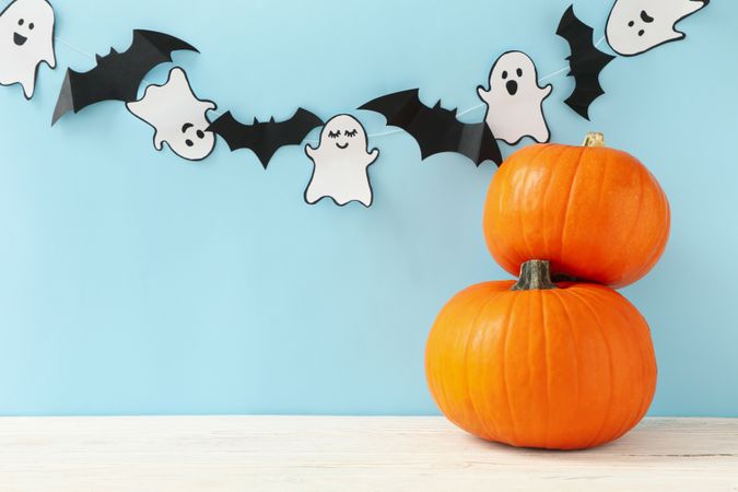 Pumpkins, paper ghosts and bats on blue background