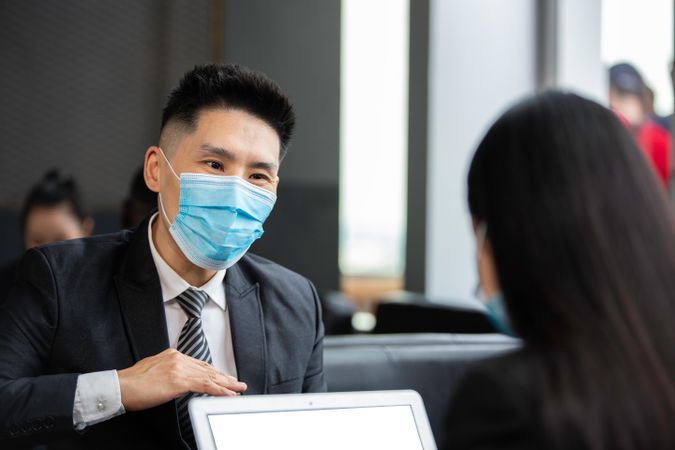 Portrait of Asian businessman wearing medical mask with colleague