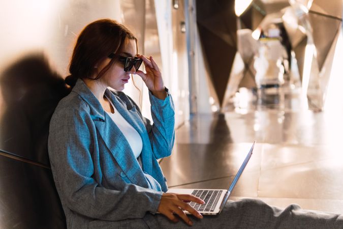 Woman in sunglasses browsing laptop in studio