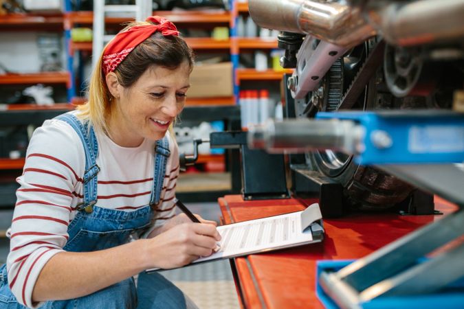 Mechanic woman filling out motorcycle documentation on garage