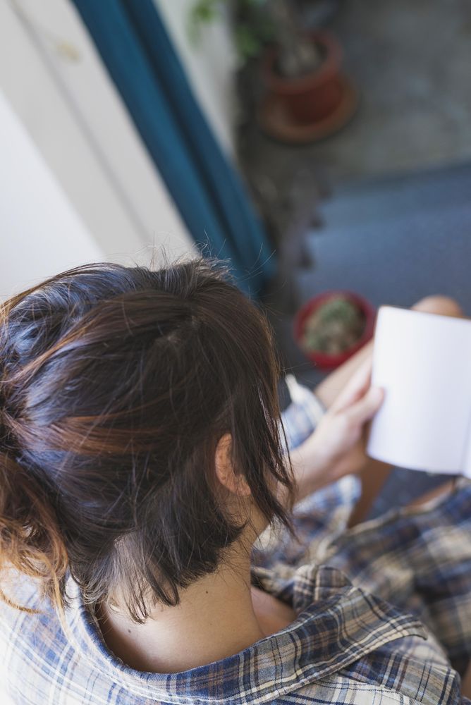 Looking over shoulder of woman reading book on stairs, copy space