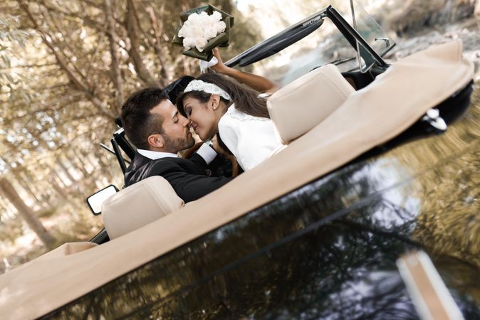 Newlyweds kissing in vintage car