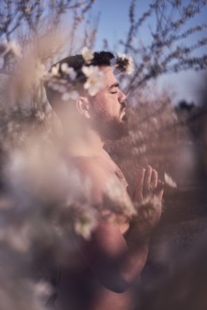 Shirtless man meditating in spring garden