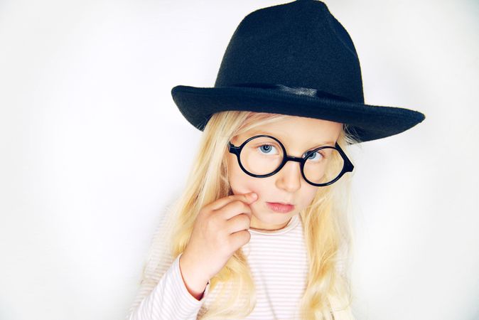 Curious blonde girl with in hat and glasses