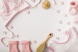 Baby clothing and pacifier on light background