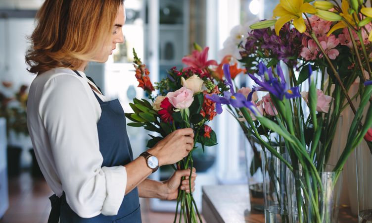 Woman working at flower shop making bouquet