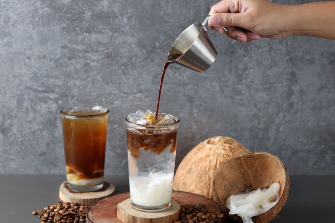 Pouring Arabica Coffee to the Glass with Fresh Coconut Juice and Coconut Flesh
