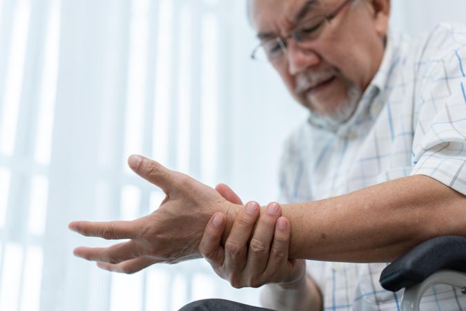 Asian man grasping his wrist to relieve pain