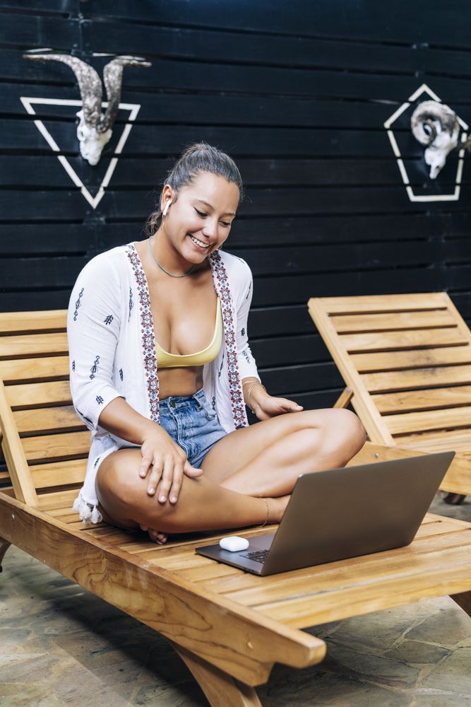 Relaxed woman using laptop while resting on deck chair