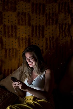 Smiling woman using smartphone in dark room