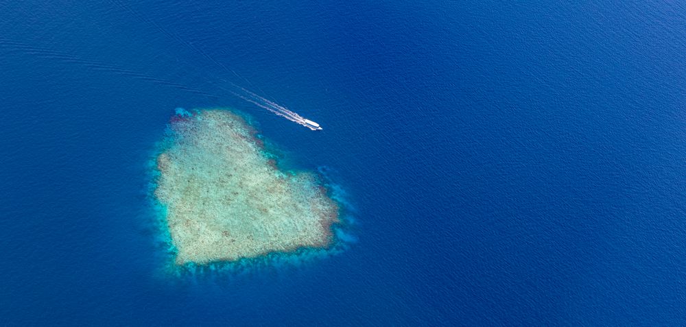 Wide shot of island in the Maldives shot from an airplane, with boat