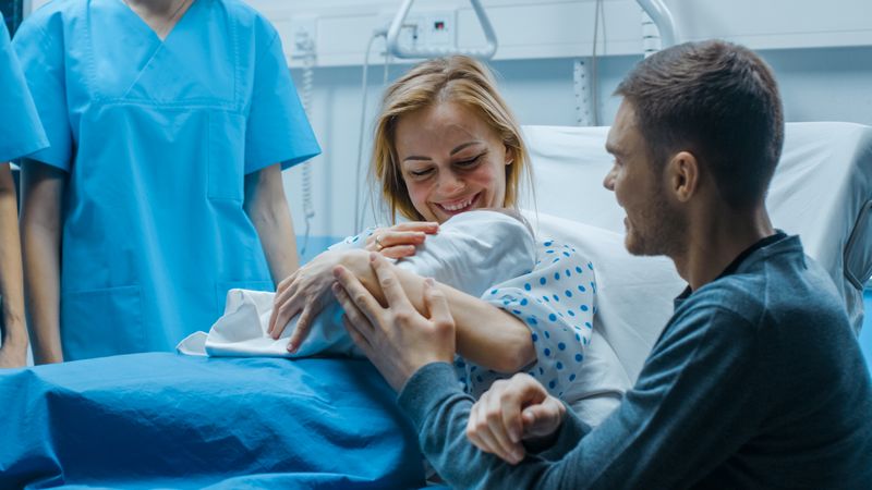 In the Hospital Mother Hold Newborn Baby, Supportive Father Lovingly Hugging Baby and Wife
