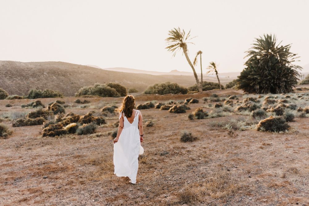 Woman in white dress in dry field in sunlight