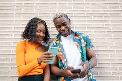 Young Black friends using smartphone in the street