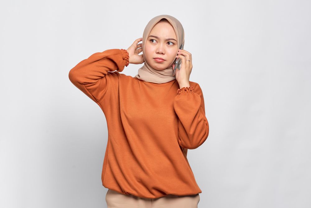 Serious Muslim woman smiling with smart phone to her ear
