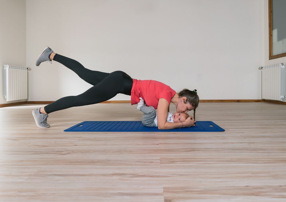 Mother exercising and kissing baby