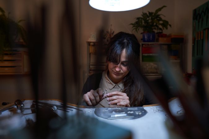 Serious female jeweler engraving with manual tool