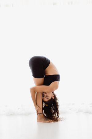 Sportive woman performing yoga pose in room