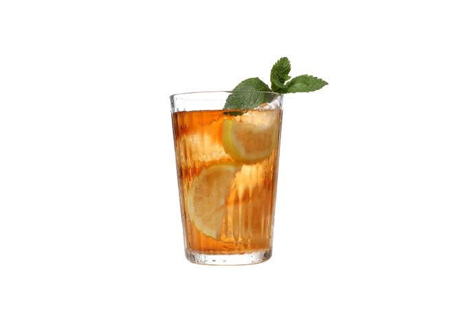 A glass of cold tea with an orange, isolated on plain background