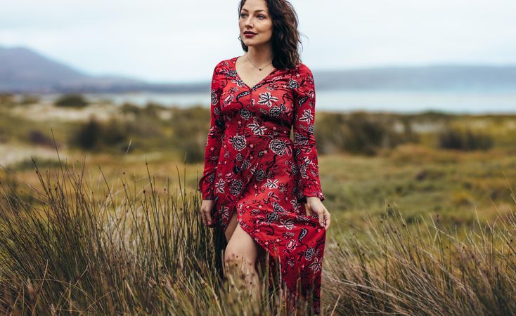 Woman walking through coastal field in red dress
