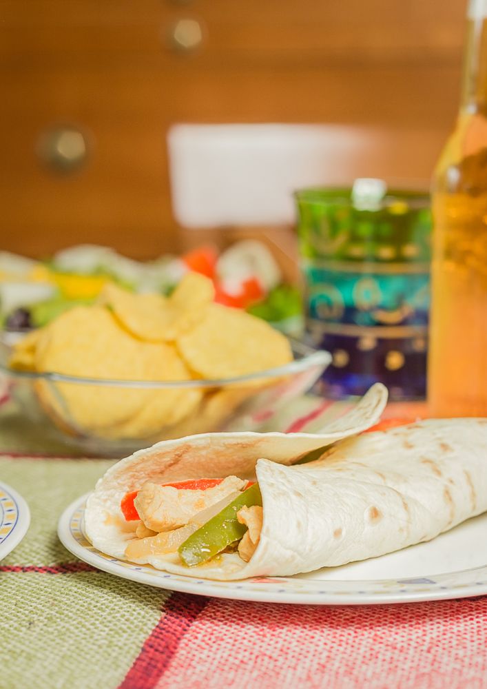 Traditional mexican food with a plate of chicken fajita, fresh salad and a bowl of nachos