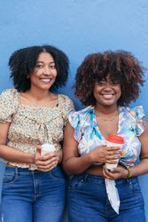 Two women drinking coffee in the street