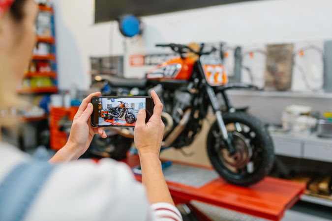 Female mechanic taking photo to motorcycle repaired on garage
