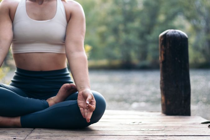 Woman meditating in nature near a lake