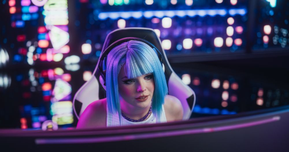 Portrait of a Stylish Streamer and Video Gamer with Blue Hair Chats with Internet Fans on Computer in Futuristic Cyber Technology Room.