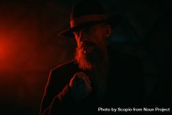 Portrait of middle aged man with fedora hat in red lit studio 41vVgb