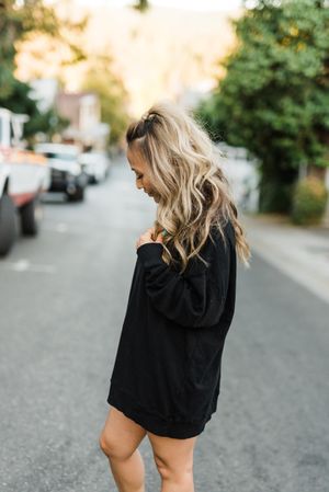 Side view of woman in dark sweater standing on road