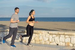 Satisfied sporty couple enjoying in run on seashore