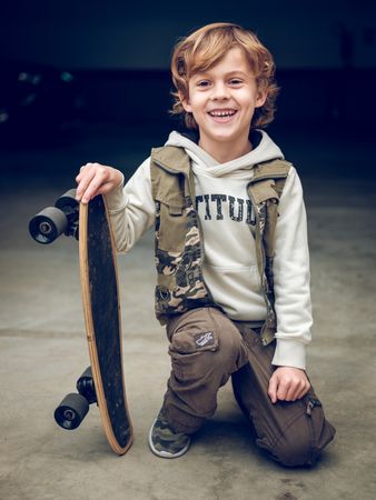 Boy with skateboard on knees