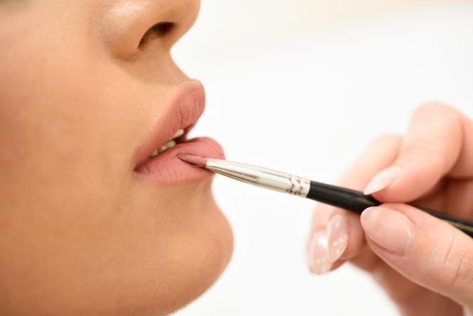 Woman having lipstick applied by a professional make up artist