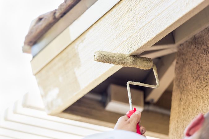 Professional Painter Using Small Roller to Paint House Fascia