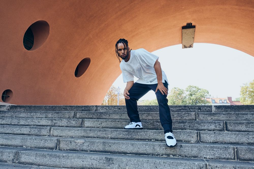 Trendy Black man posing near modern arch