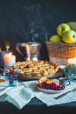 Sweet baked pie with fruit filling on table with basket of apples
