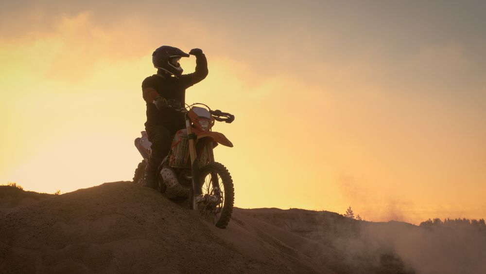 Professional Motocross Biker Spectacularly Stands on the Off-Road Dune on his Enduro Motorcycle.