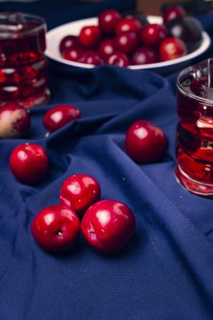Red beverage near fresh fruits on cloth