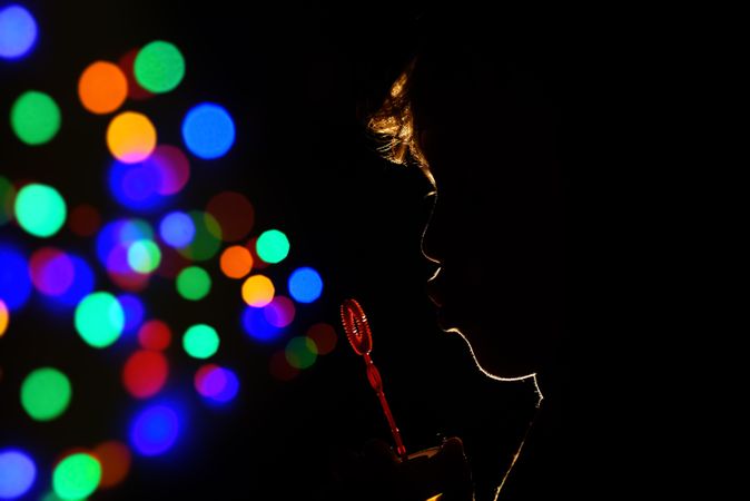 Anonymous kid blowing bubbles in darkness