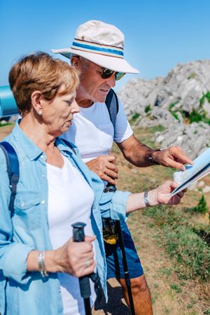Older couple checking map on trek
